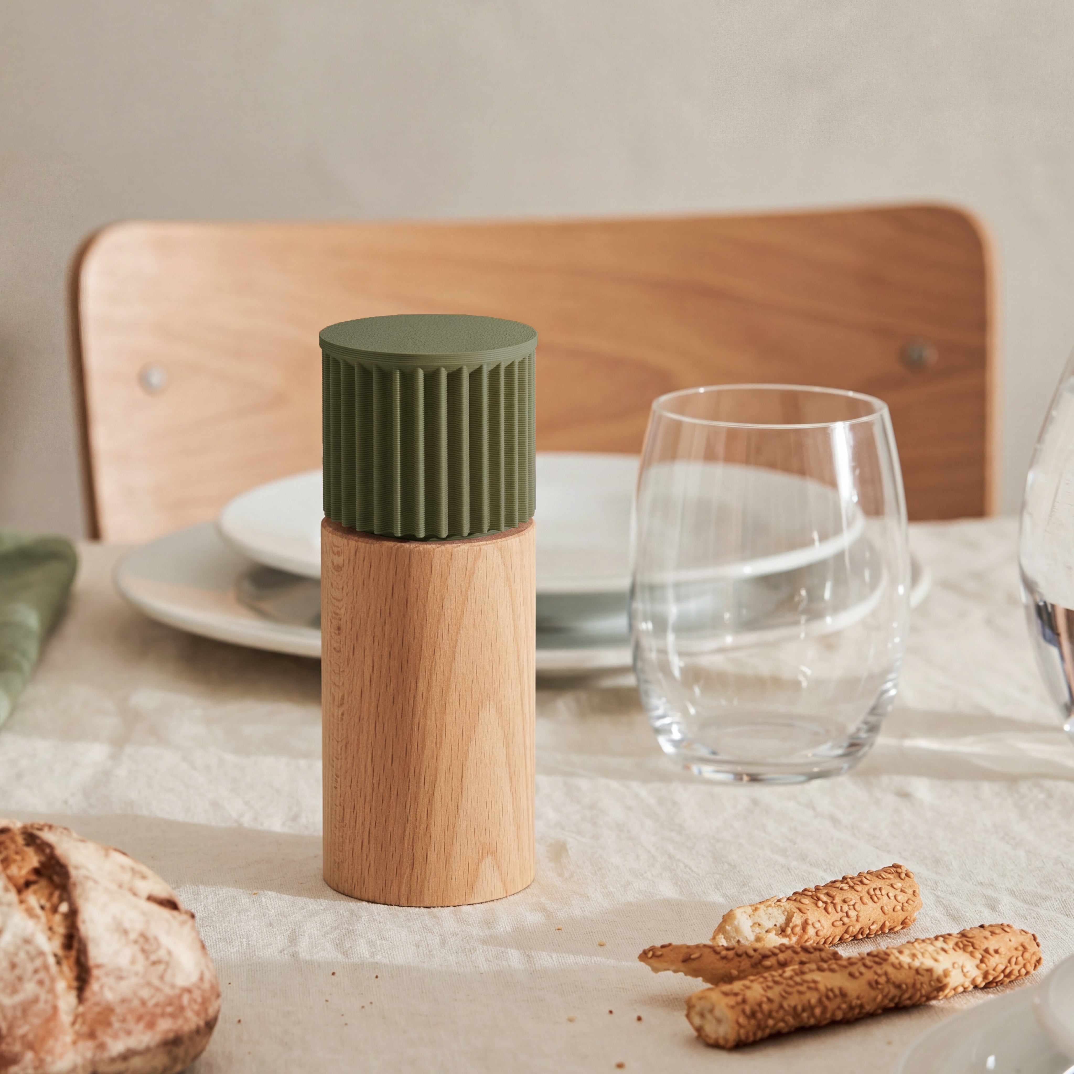 Gewürzmühle Prise in olivgrün aus Buchenholz auf gedecktem Tisch mit Brot und Wasserglas #farbe_olivgrün