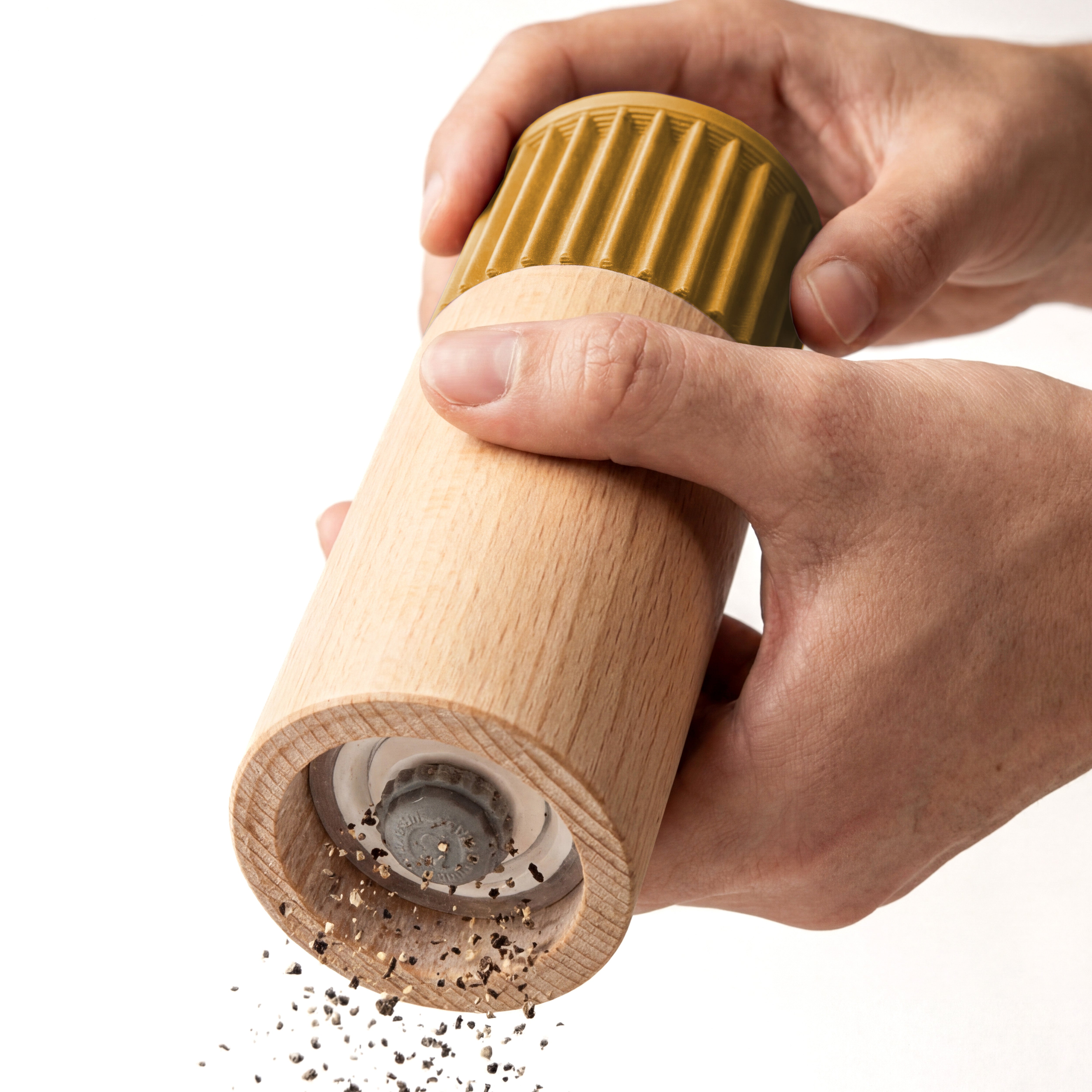 Hände mahlen Pfeffer mit der Gewürzmühle Prise in senfgelb aus Buchenholz vor weißem Grund #farbe_senfgelb