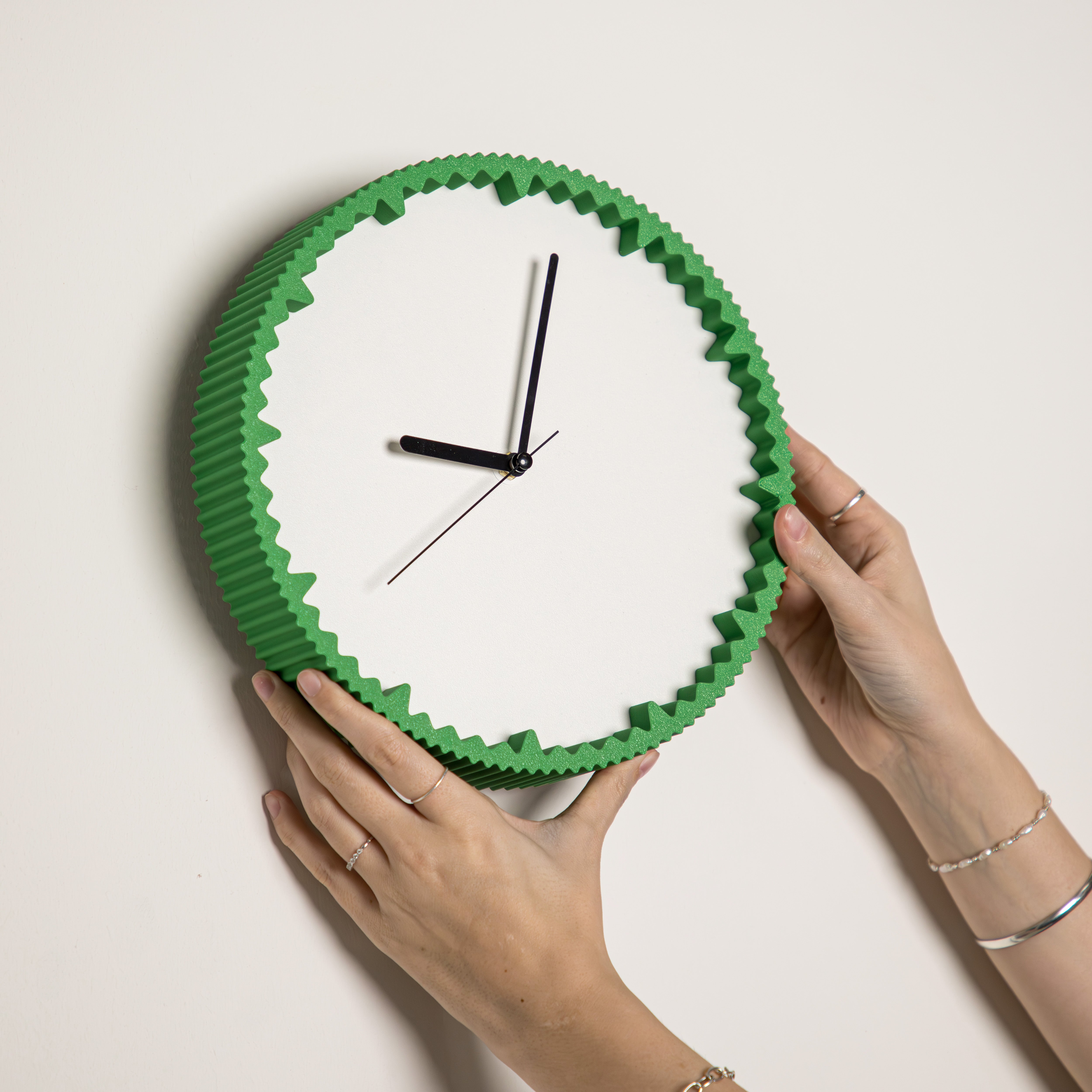 Hände hängen moderne grüne Wanduhr mit gezacktem Rand aus dem 3D Druck an die Wand #farbe_grün
