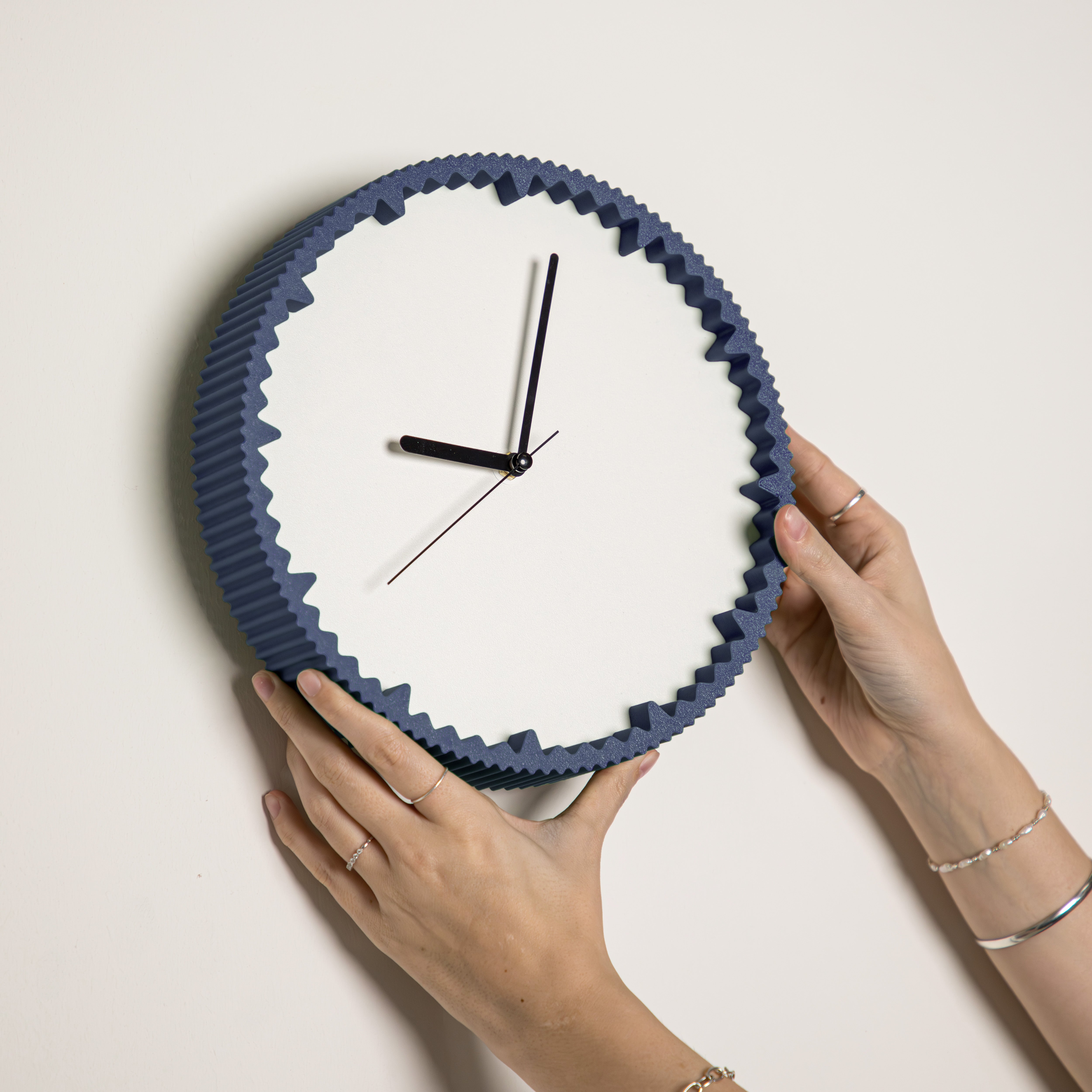 Hände hängen moderne Wanduhr navyblau mit gezacktem Rand aus dem 3D Druck an die Wand #farbe_navyblau