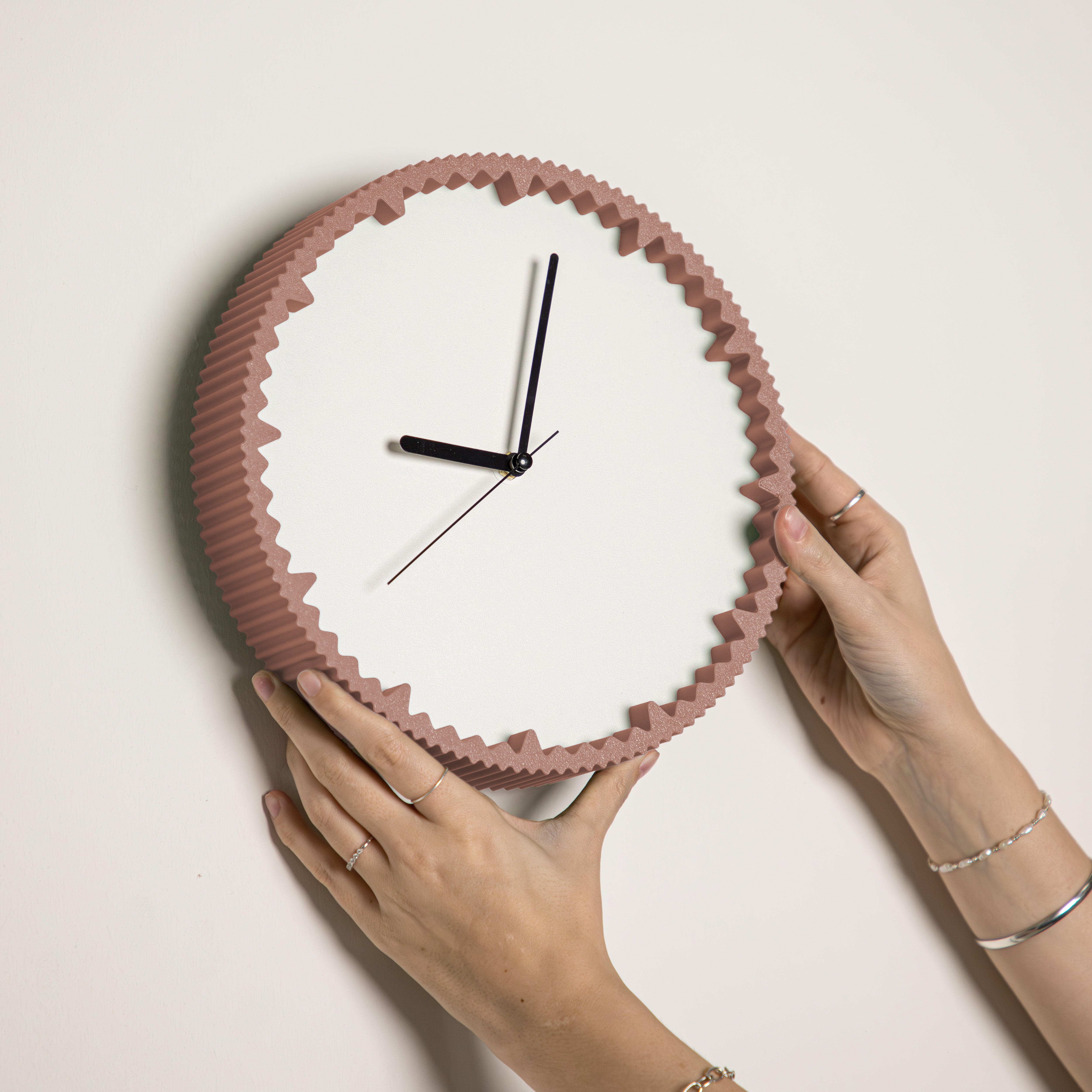 Hände hängen moderne Wanduhr terracotta mit gezacktem Rand aus dem 3D Druck an die Wand #farbe_terracotta