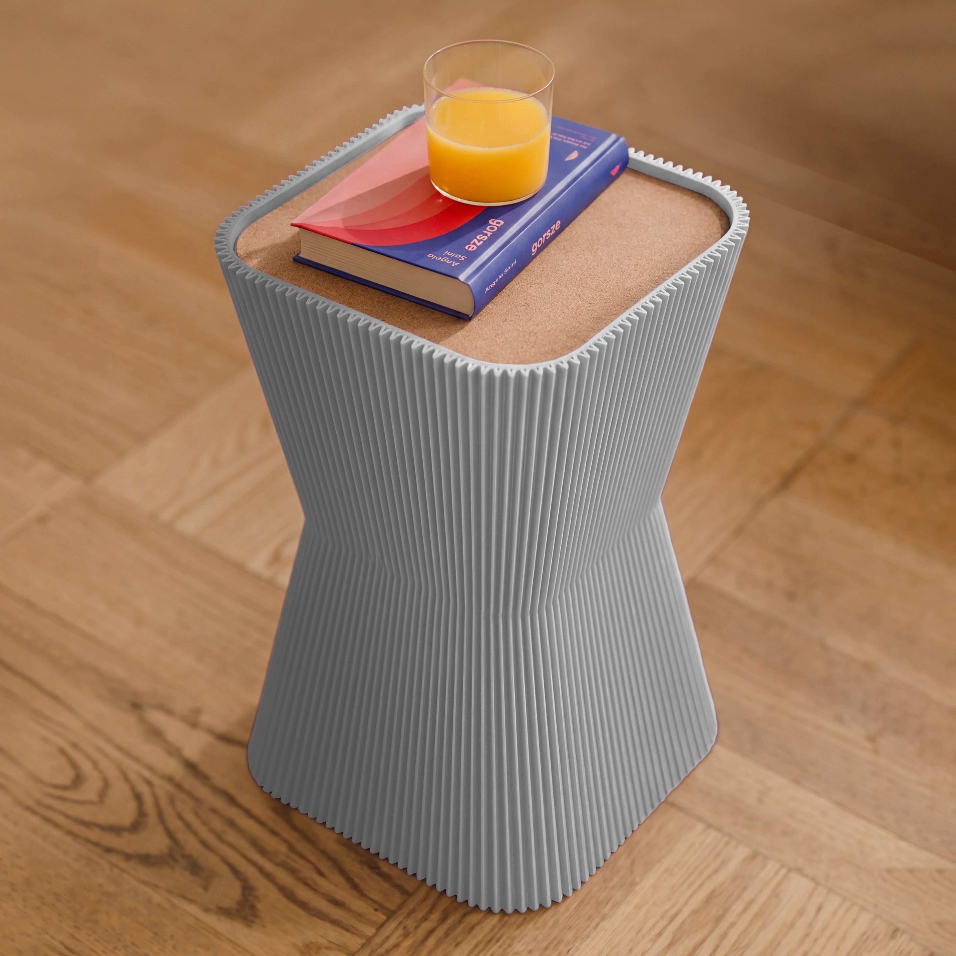 Beistelltisch Pyramide in grau aus dem 3D Druck mit Buch und Orangensaft auf dem Korkdeckel #farbe_hellgrau