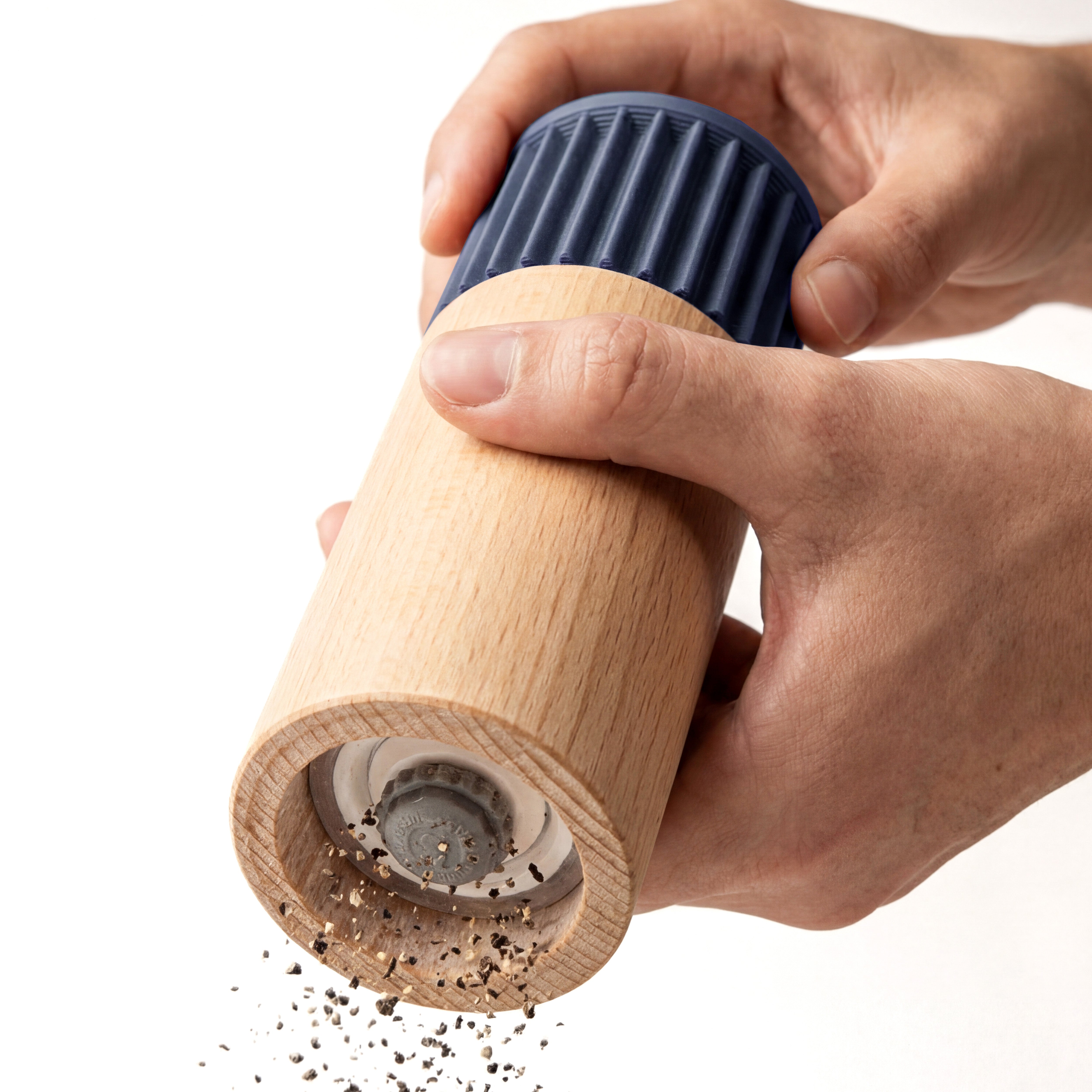Hände mahlen Pfeffer mit der Gewürzmühle Prise in Navyblau aus Buchenholz vor weißem Grund #farbe_navyblau