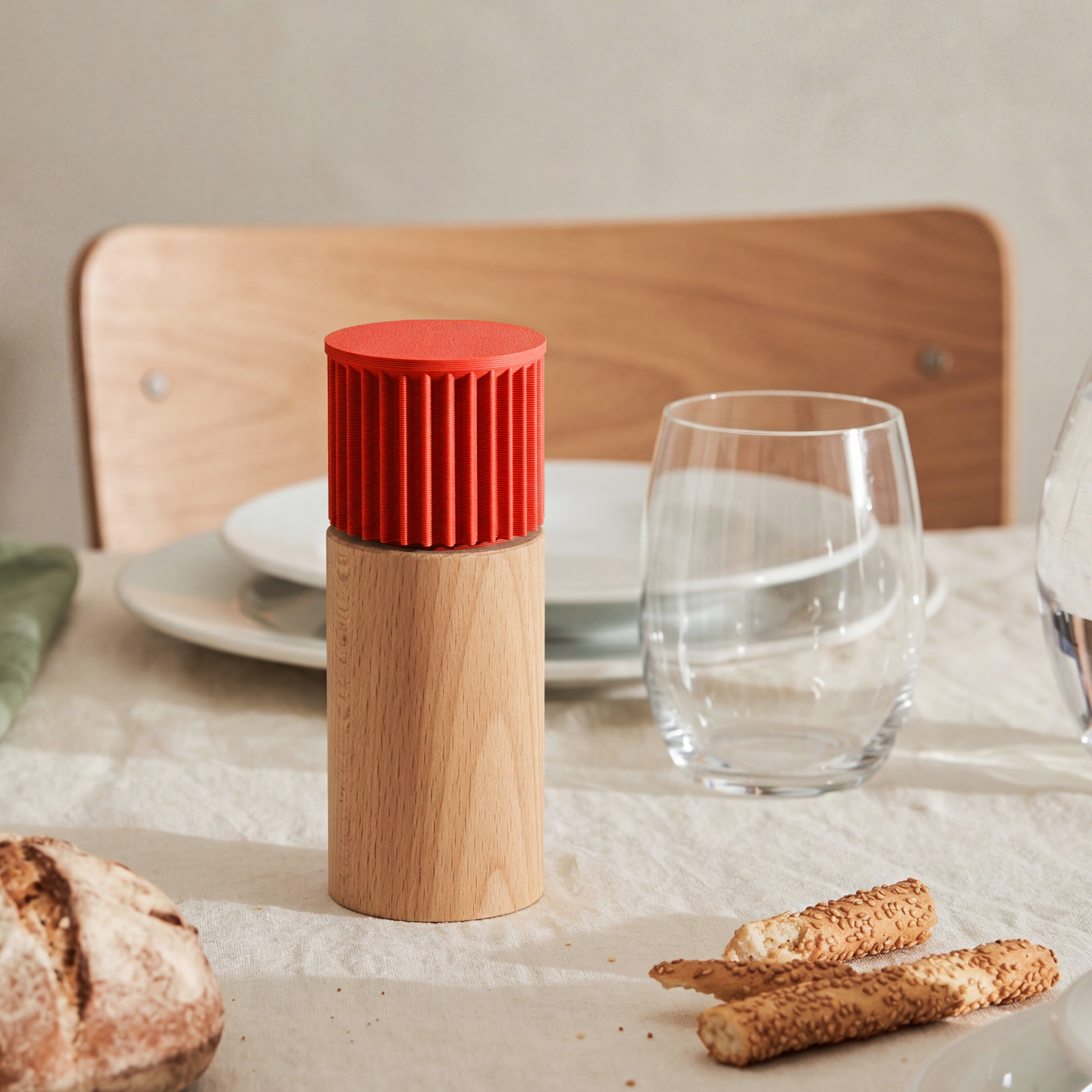Gewürzmühle Prise in rot aus Buchenholz auf gedecktem Tisch mit Brot und Wasserglas #farbe_rot
