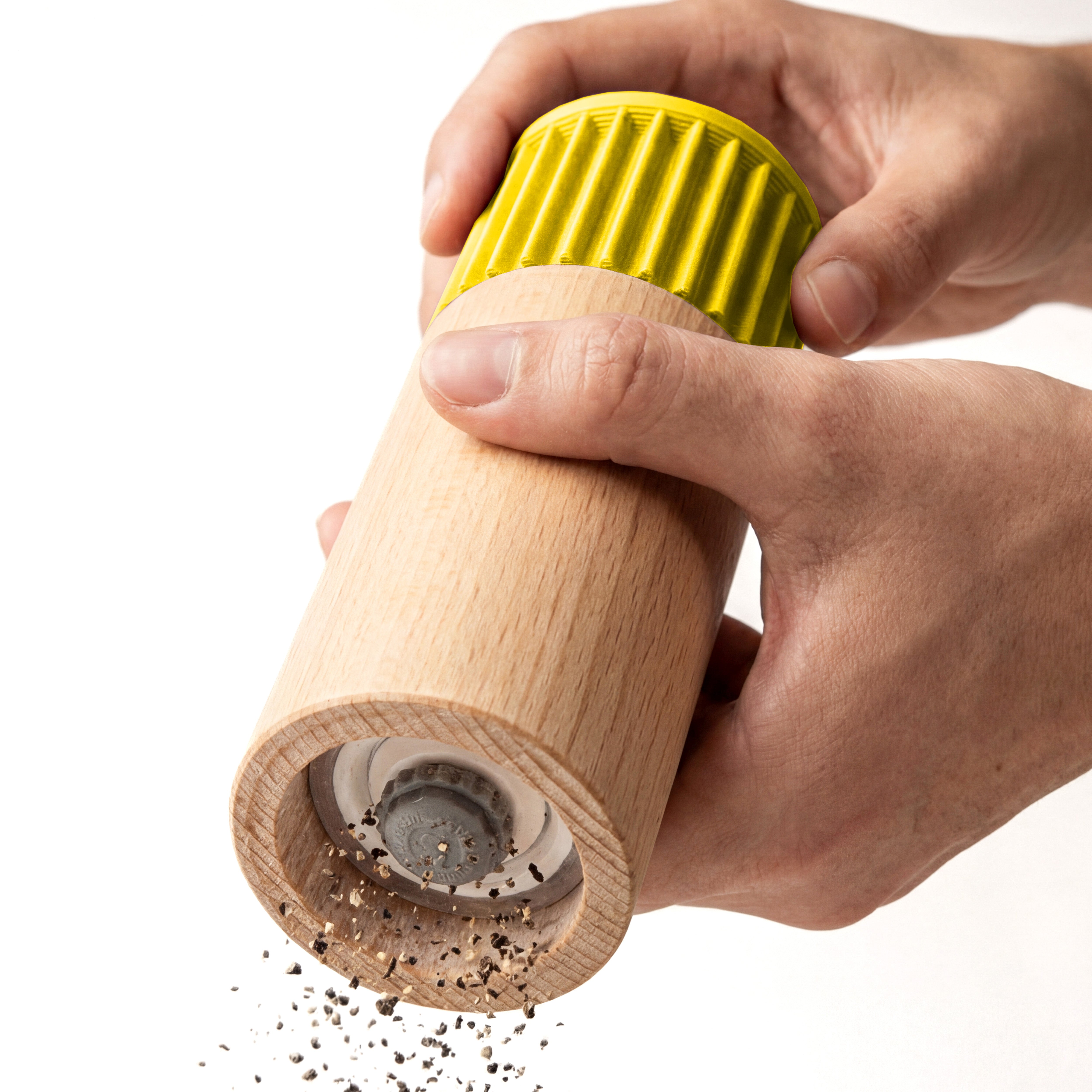 Hände mahlen Pfeffer mit der Gewürzmühle Prise in Gelb aus Buchenholz vor weißem Grund #farbe_gelb