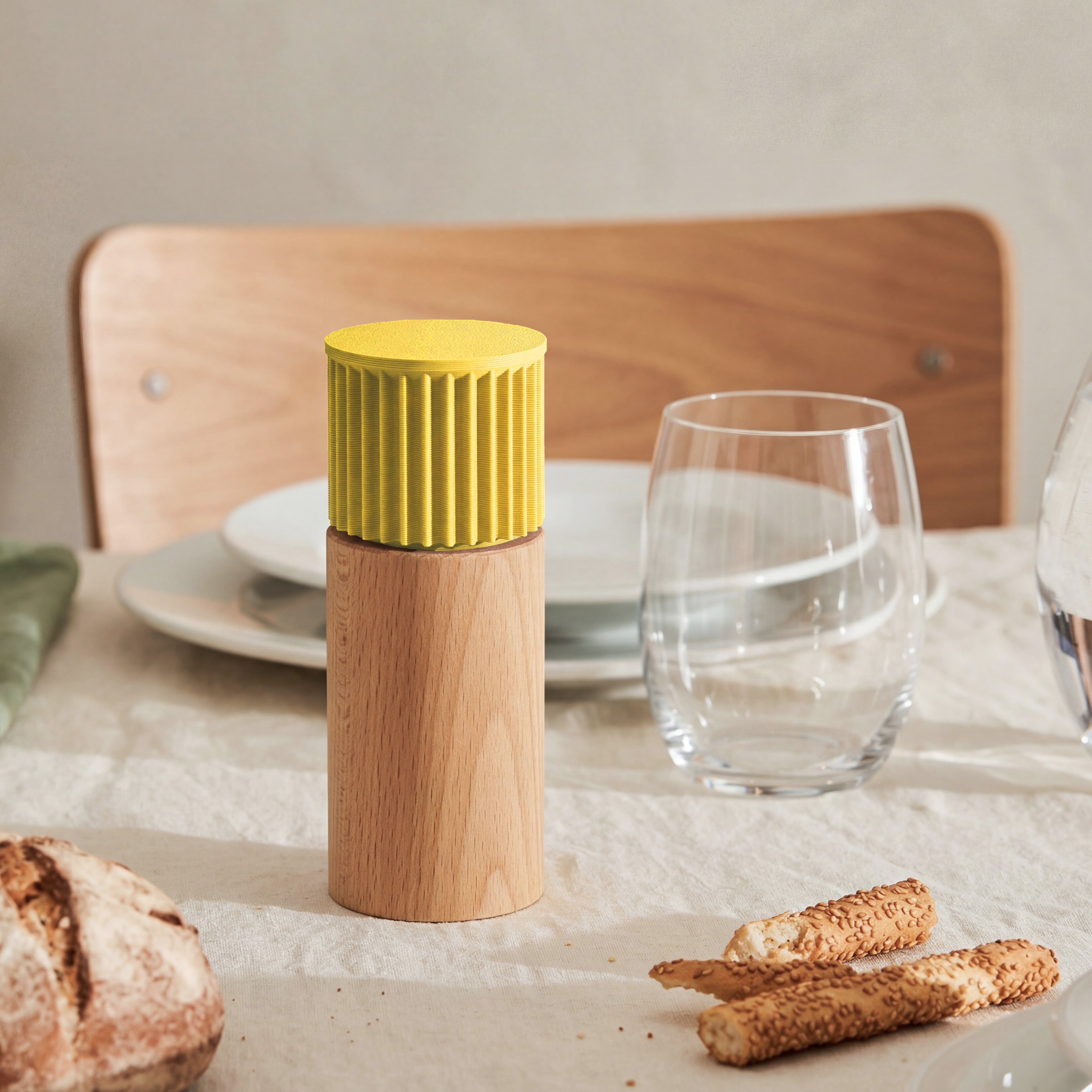 Gewürzmühle Prise in gelb aus Buchenholz auf gedecktem Tisch mit Brot und Wasserglas #farbe_gelb