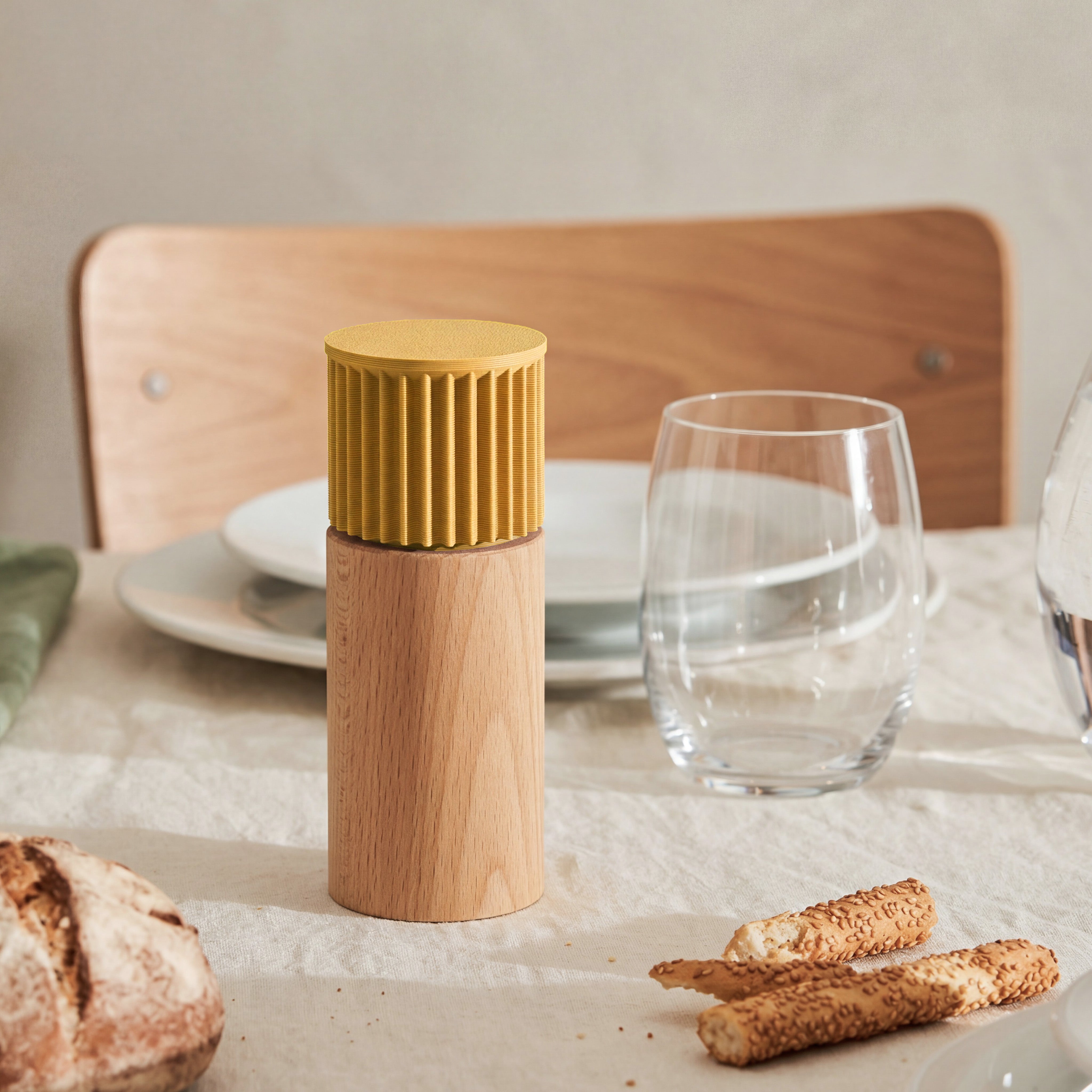 Gewürzmühle Prise in senfgelb aus Buchenholz auf gedecktem Tisch mit Brot und Wasserglas #farbe_senfgelb