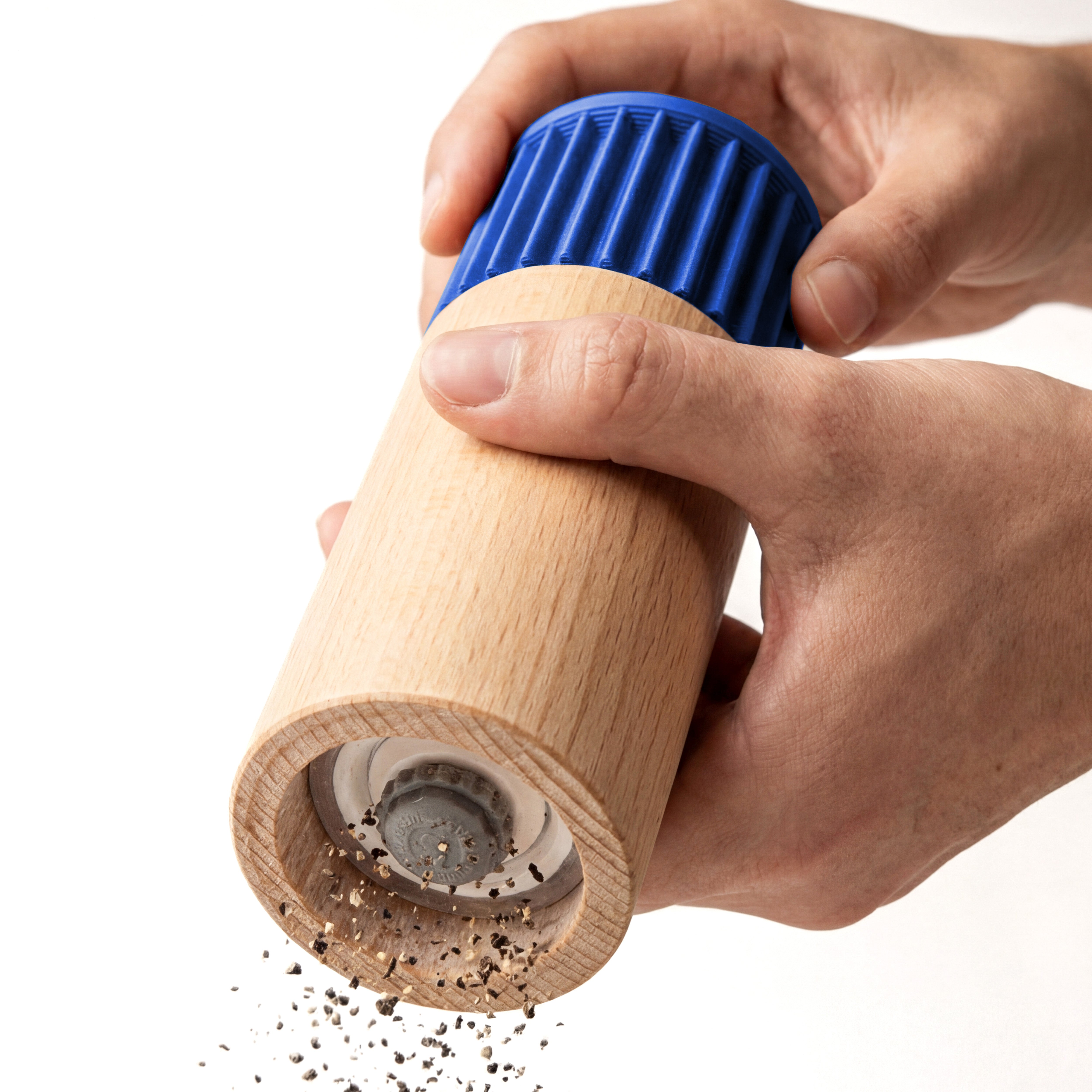 Hände mahlen Pfeffer mit der Gewürzmühle Prise in blau aus Buchenholz vor weißem Grund #farbe_blau