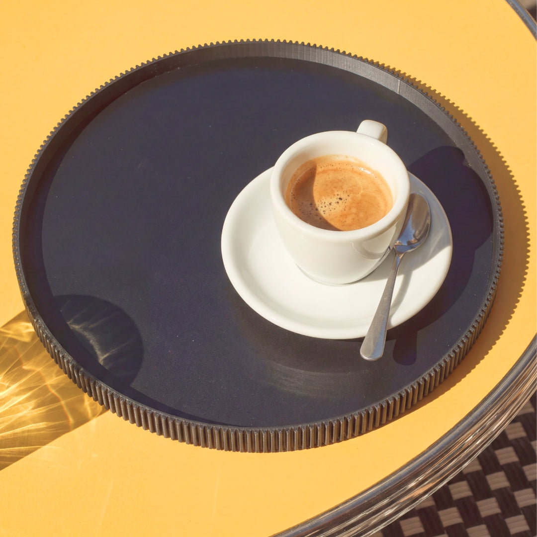 Rundes Deko-Tablett in Schwarz aus dem 3D Druck mit Espressotasse von oben auf gelbem Tisch