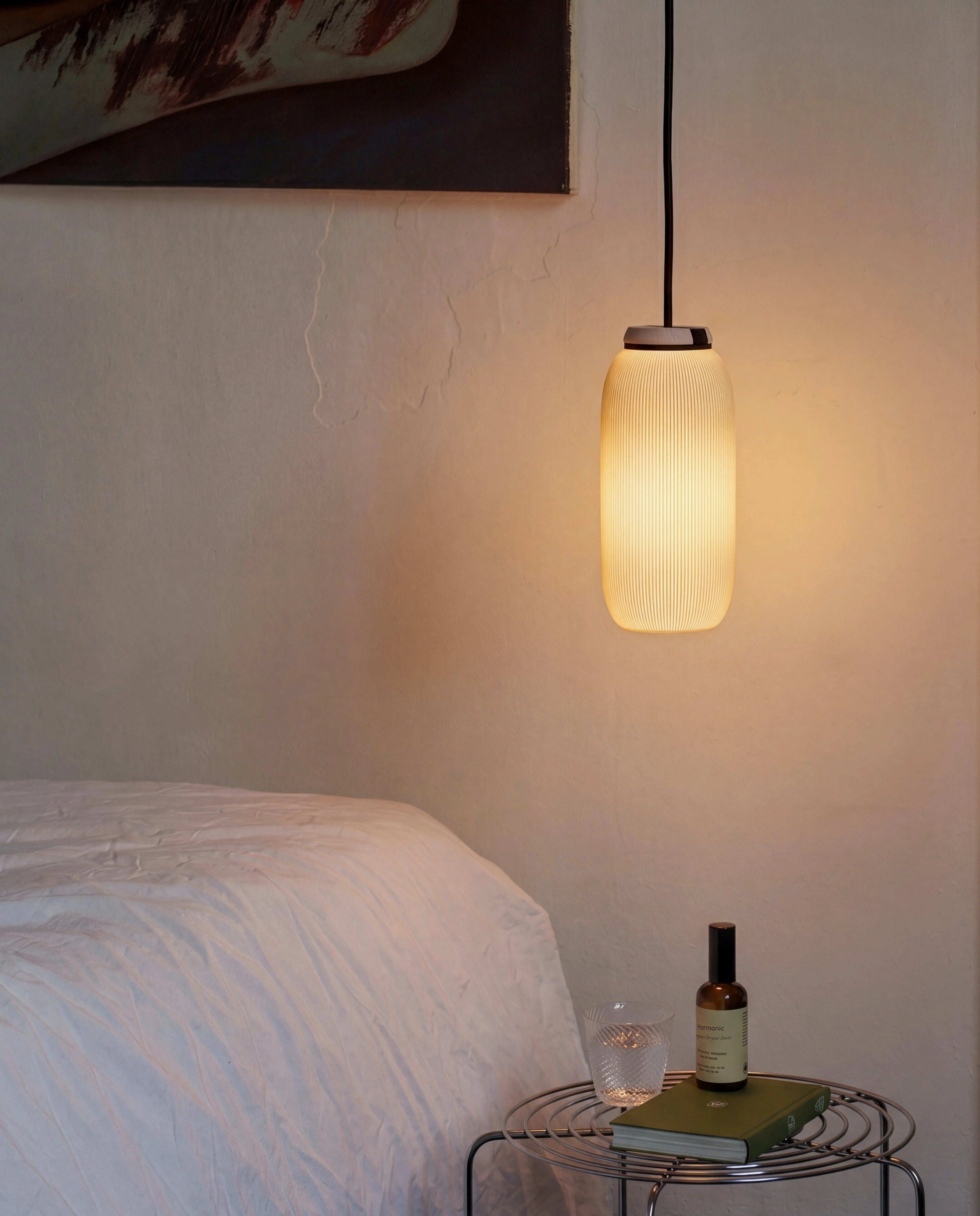 Pendelleuchte Pille mit warmem Licht über Nachttisch mit Buch und Glas im Schlafzimmer