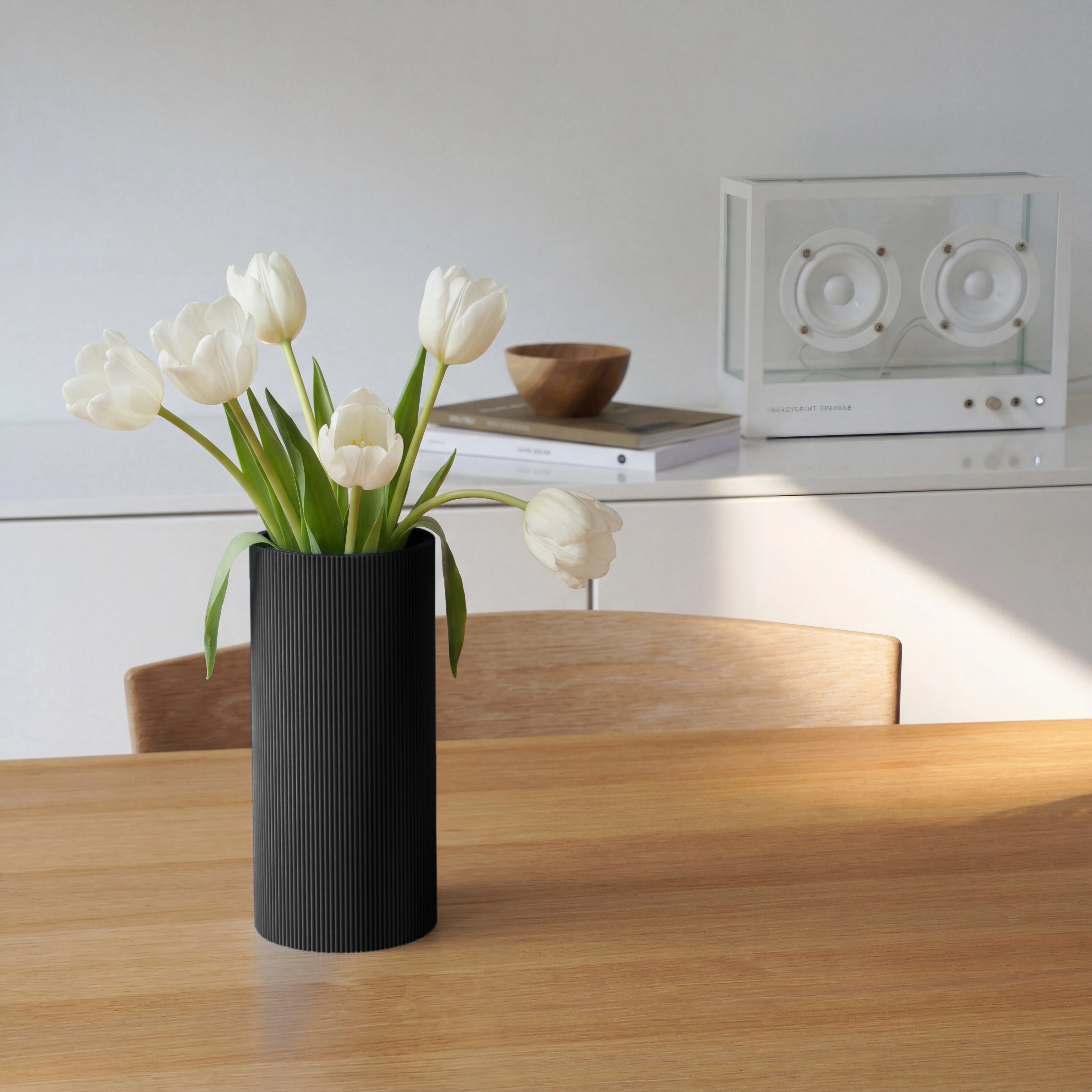 Schwarze Vase aus dem 3D Druck mit gerader Form und weißen Tulpen auf Holztisch