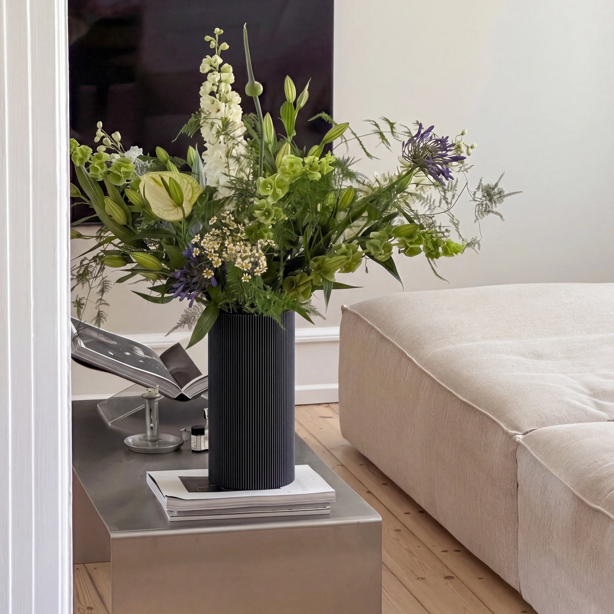 Schwarze Vase GERADE aus 3D Druck mit großem Blumenstrauß auf einem Beistelltisch aus Edelstahl