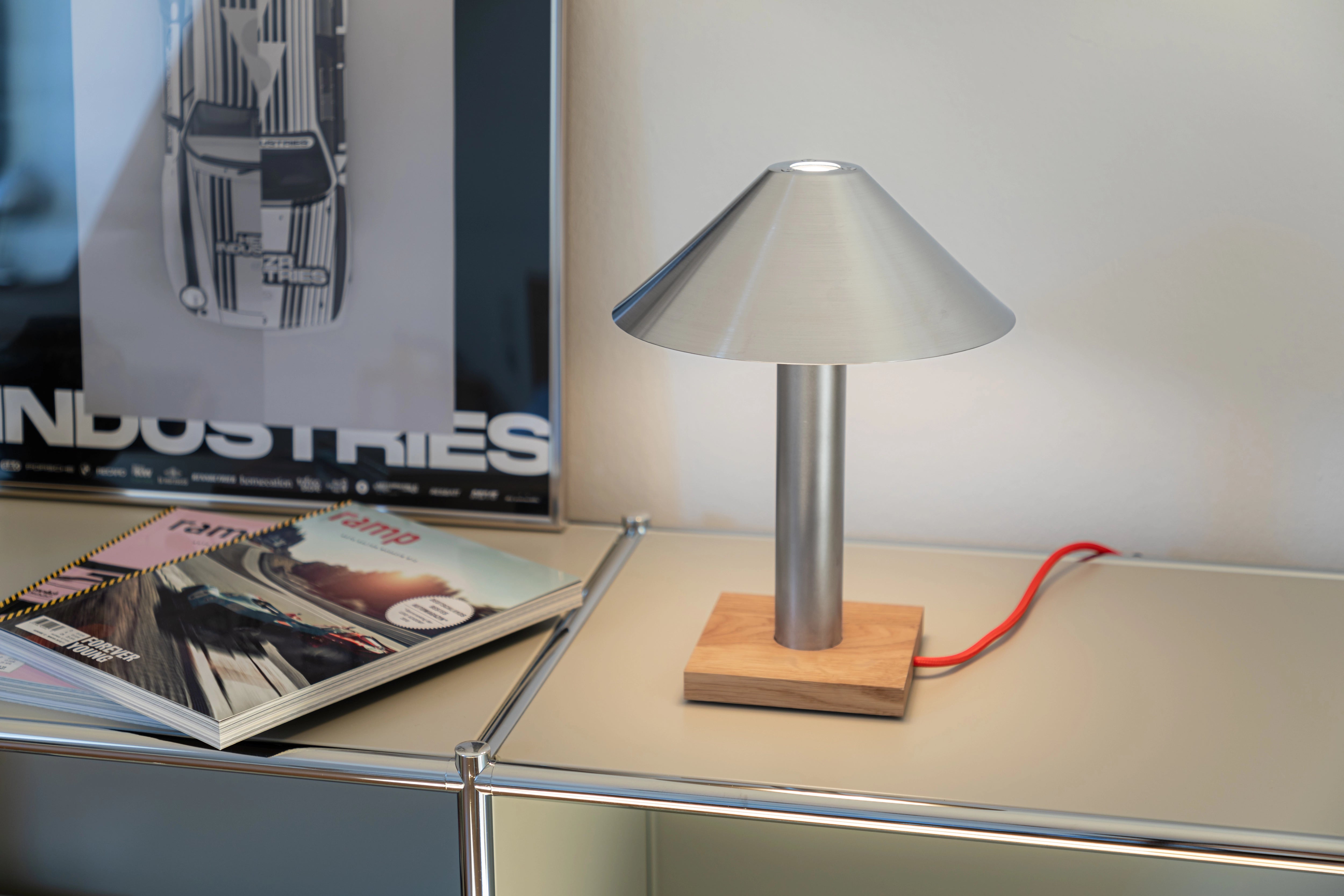 Tischlampe PFEIL aus Edelstahl mit Eichenholzsockel und rotem Textilkabel auf hellem Sideboard
